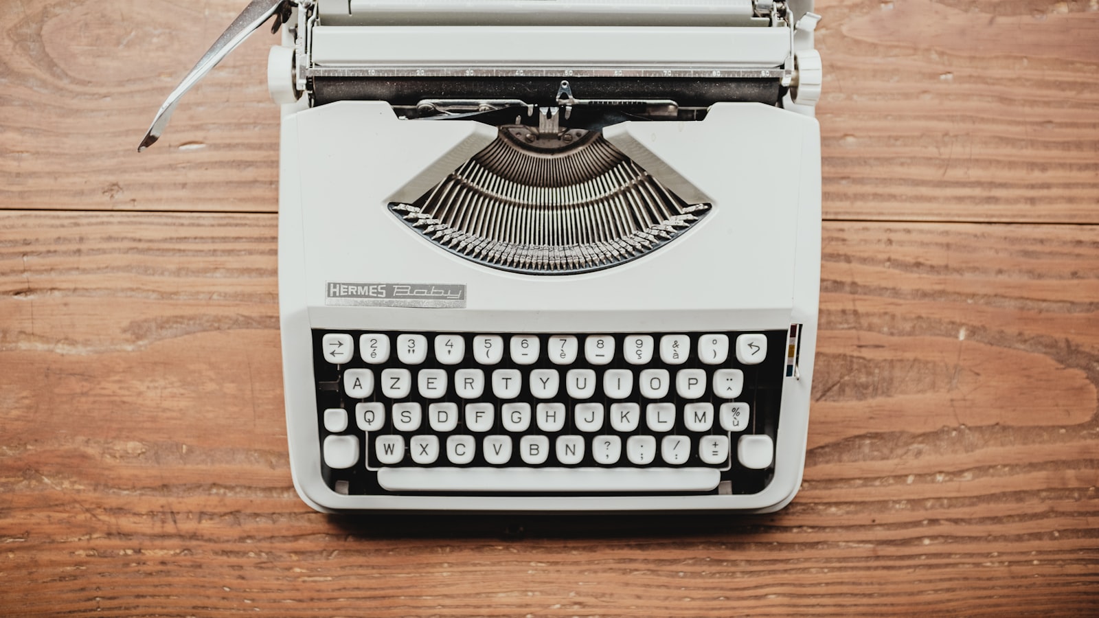 A vintage typewriter on a wooden desk, seen from above