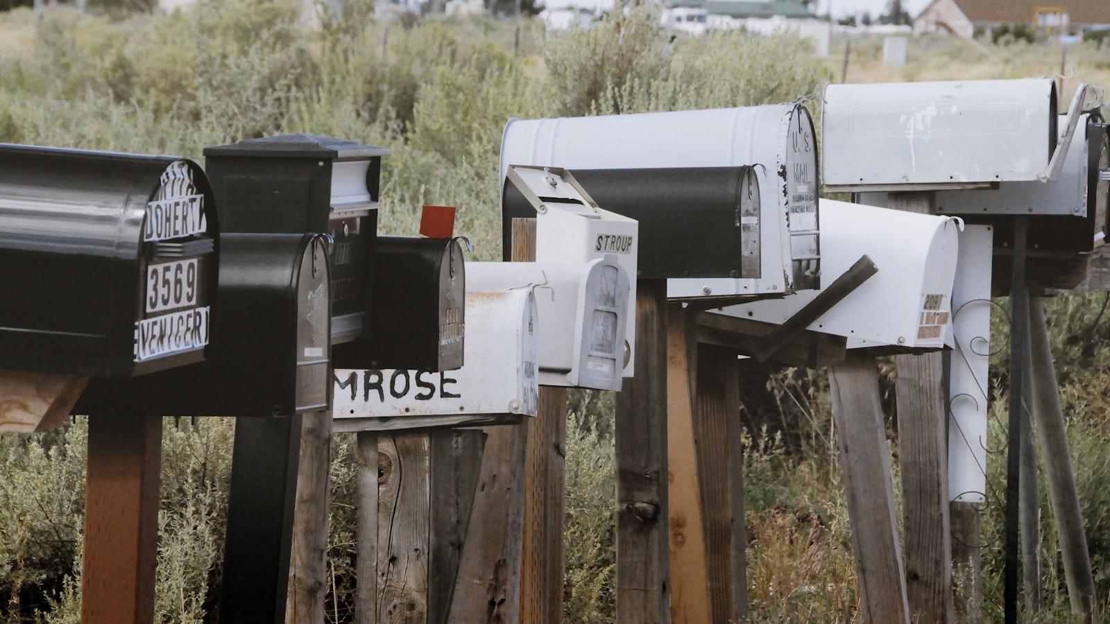 A row of weathered roadside mailboxes on wooden posts
