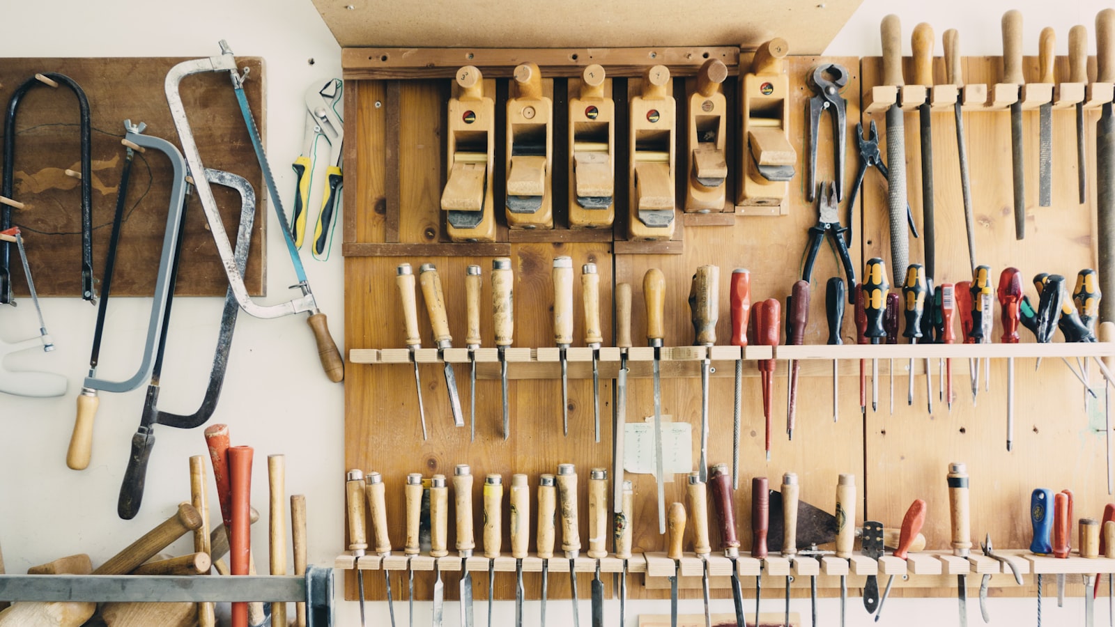A woodworking wall rack holding neat rows of hand tools